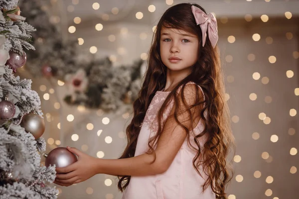 Beautiful little girl in a pink dress near the New Year tree — Stock Photo, Image