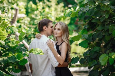 Young beautiful couple in the summer garden enjoys tranquility and relaxation