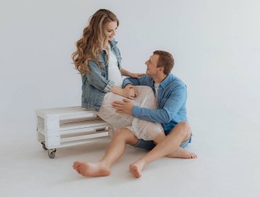 Shot of pretty young pregnant couple in the white room at home.