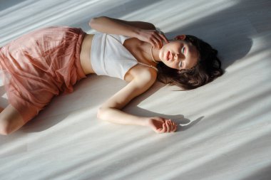 Beautiful sexy brunette girl lying on the floor. beautiful light from the window