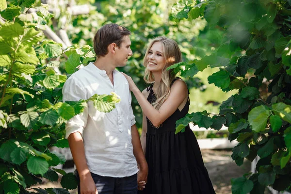 Young beautiful couple in the summer garden enjoys tranquility and relaxation — Stok fotoğraf