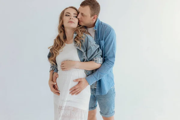 Shot of pretty young pregnant couple in the white room at home. — Stockfoto