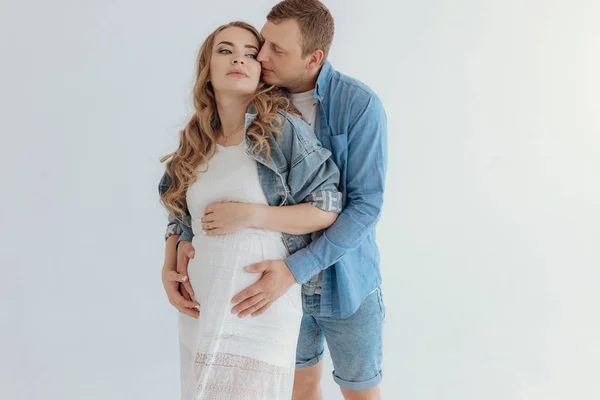 Tiro de casal grávida muito jovem na sala branca em casa . — Fotografia de Stock