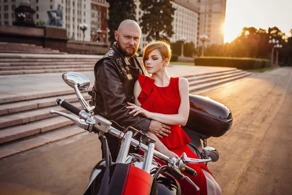 Vackra ovanliga par på en motorcykel mot bakgrund av en vacker ståtlig byggnad i Moskva — Stockfoto