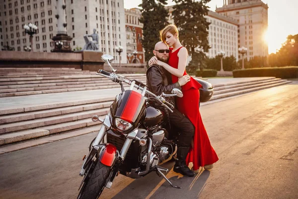Vackra ovanliga par på en motorcykel mot bakgrund av en vacker ståtlig byggnad i Moskva — Stockfoto