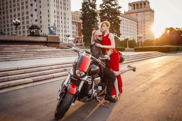 Beautiful unusual couple on a motorcycle against the backdrop of a beautiful stately building in Moscow — ストック写真