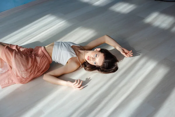 Beautiful sexy brunette girl lying on the floor. beautiful light from the window — Stok fotoğraf