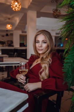 Elegant lady with glass of wine alone in restaurant