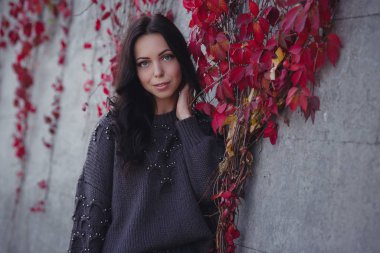 Girl on background wall with red autumn leaves.