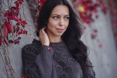 Girl on background wall with red autumn leaves.