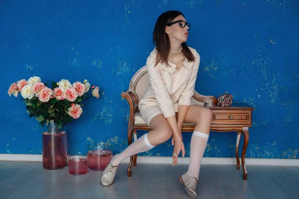 Mujer mariquita en el vestido rosa está posando cerca de la pared de textura azul —  Fotos de Stock