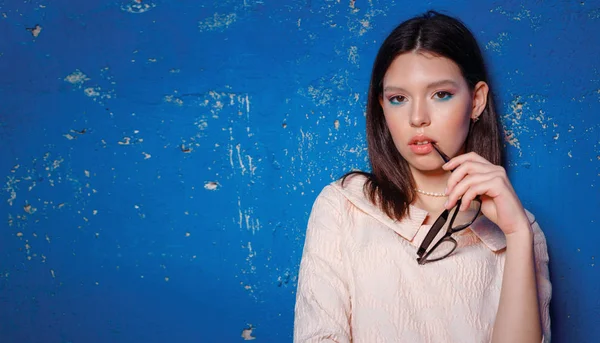 Mujer mariquita en el vestido rosa está posando cerca de la pared de textura azul — Foto de Stock