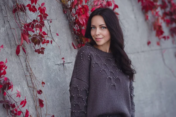 Girl on background wall with red autumn leaves.