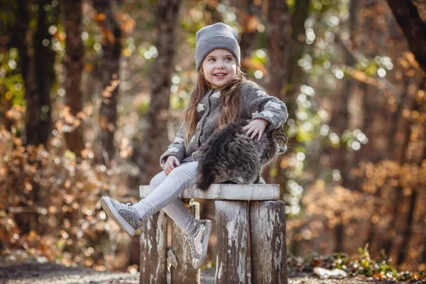 Little cute girl and cat in the forest, soft warm light — ストック写真