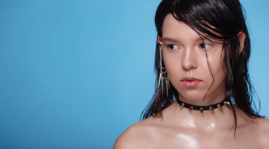 Arka plandaki stüdyoda piercingli ve diğer aksesuarlı güzel Gotik kadın portresi. Duygusal, genç yüz. İnsani duygular, yüz ifadesi kavramı. Pankartta moda renkleri