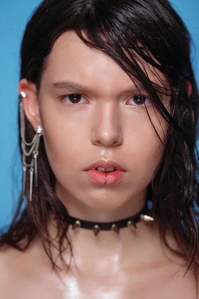 Arka plandaki stüdyoda piercingli ve diğer aksesuarlı güzel Gotik kadın portresi. Duygusal, genç yüz. İnsani duygular, yüz ifadesi kavramı - saldırganlık ve şüphe .