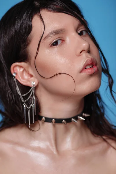 Portrait of beautiful Gothic woman with piercings and other accessories in studio on bue background. Emotional, young face. Human emotions, facial expression concept - calm and peace. Trendy colors