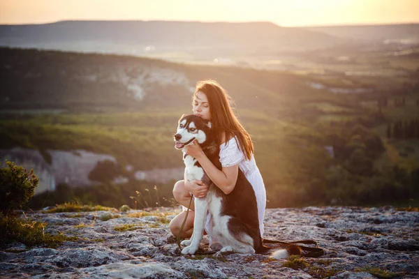 高い山の中に座って晴れた日にハスキー犬と若い女性 自由と幸福の概念 観光と冒険 — ストック写真