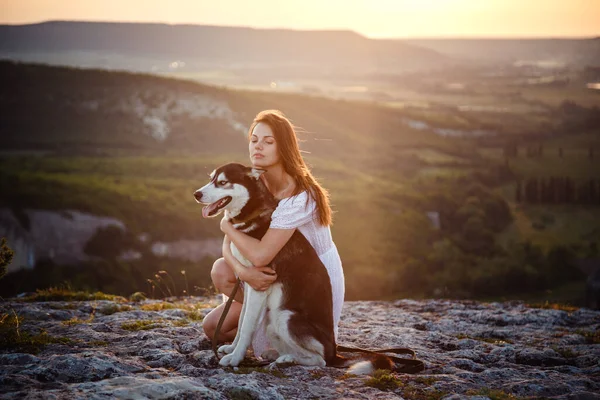 高い山の中に座って晴れた日にハスキー犬と若い女性 自由と幸福の概念 観光と冒険 — ストック写真