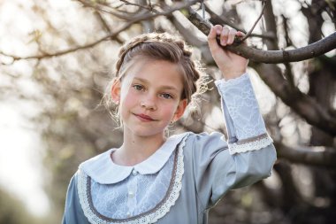 6-7 yaşlarında güzel bir kız bahçede poz veriyor. Paskalya zamanı. Bahar ve sıcağı seviyor. Güzel bir bahar bahçesi. Mutlu çocukluk, huzur ve mutluluk konsepti. Aromatik çiçekler ve antika mahsuller.