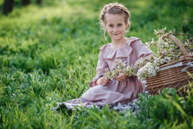 6-7 yaşlarında güzel bir kız bahçede poz veriyor. Paskalya zamanı. Bahar ve sıcağı seviyor. Güzel bir bahar bahçesi. Mutlu çocukluk, huzur ve mutluluk konsepti. Aromatik çiçekler ve antika mahsuller.