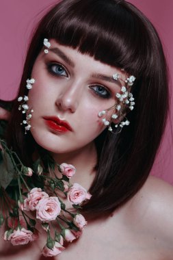 Taze, pürüzsüz bir teni, pembe arka planda çiçekli çıplak makyajı olan genç ve güzel bir kadının stüdyo güzelliği portresini kapat. Moda fotoğrafı.