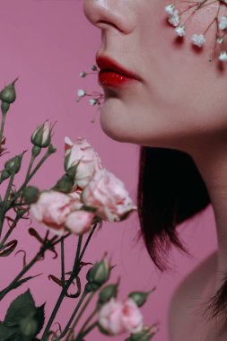Taze, pürüzsüz bir teni, pembe arka planda çiçekli çıplak makyajı olan genç ve güzel bir kadının stüdyo güzelliği portresini kapat. Moda fotoğrafı.