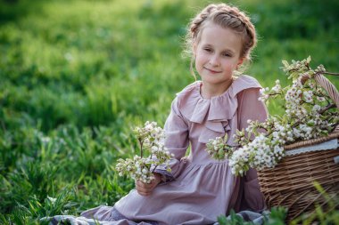 6-7 yaşlarında güzel bir kız bahçede poz veriyor. Paskalya zamanı. Bahar ve sıcağı seviyor. Güzel bir bahar bahçesi. Mutlu çocukluk, huzur ve mutluluk konsepti. Aromatik çiçekler ve antika mahsuller.
