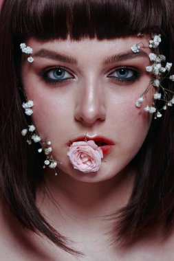 Taze, pürüzsüz bir teni, pembe arka planda çiçekli çıplak makyajı olan genç ve güzel bir kadının stüdyo güzelliği portresini kapat. Moda fotoğrafı.