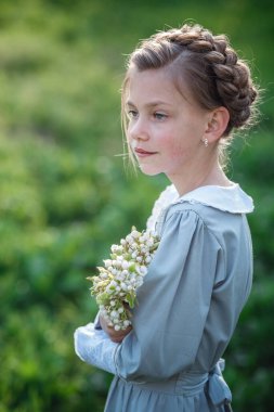 6-7 yaşlarında güzel bir kız bahçede poz veriyor. Paskalya zamanı. Bahar ve sıcağı seviyor. Güzel bir bahar bahçesi. Mutlu çocukluk, huzur ve mutluluk konsepti. Aromatik çiçekler ve antika mahsuller.