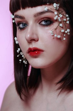 Taze, pürüzsüz bir teni, pembe arka planda çiçekli çıplak makyajı olan genç ve güzel bir kadının stüdyo güzelliği portresini kapat. Moda fotoğrafı.