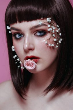 Taze, pürüzsüz bir teni, pembe arka planda çiçekli çıplak makyajı olan genç ve güzel bir kadının stüdyo güzelliği portresini kapat. Moda fotoğrafı.