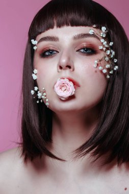 Taze, pürüzsüz bir teni, pembe arka planda çiçekli çıplak makyajı olan genç ve güzel bir kadının stüdyo güzelliği portresini kapat. Moda fotoğrafı.