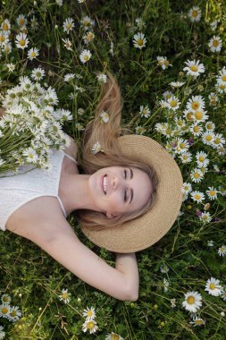 Resimli bir vadideki papatya tarlasında güzel bir genç kadın. Kişisel bakım fikri, sağlıklı bir yaşam tarzı ve olumlu bir tutum. Sağlıklı kar beyazı gülümseme, sağlıklı cilt ve saç kavramı