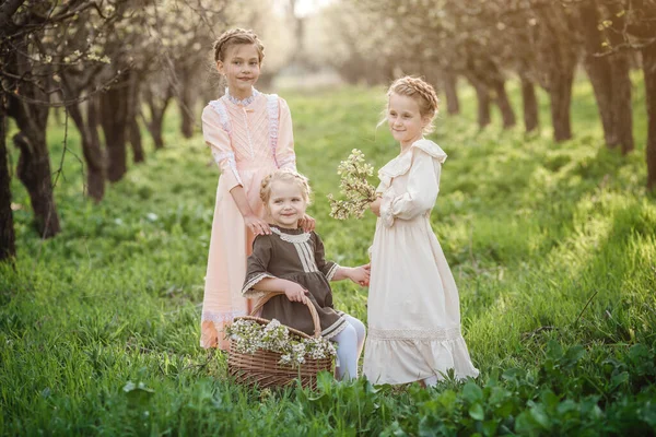 三个穿着复古服装的漂亮姑娘在一个花园子里散步 友好家庭和幸福童年的理念和概念 — 图库照片