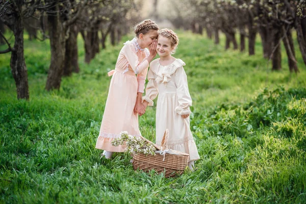 2人の姉妹やガールフレンドが庭を歩いていて 美しいヴィンテージのドレスで春を楽しんでいます 優しい家族と幸せな子供時代のアイデアとコンセプト イースターの時間と目覚め — ストック写真