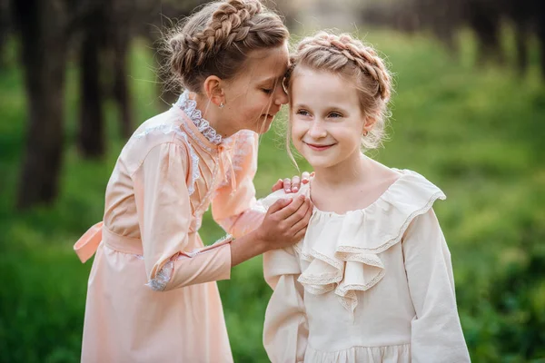 两个姐姐或女朋友穿着漂亮的老式服装在花园里散步 享受春天的到来 友好家庭和幸福童年的理念和概念 复活节时间和觉醒 — 图库照片