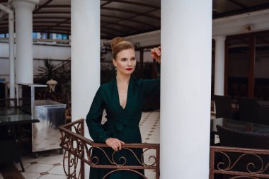 Teras restoranında bir etkinlik bekleyen güzel genç bir kadın. Şenlik ve etkinliklere hazırlanıyorum. Deniz manzaralı lüks bir elbise.