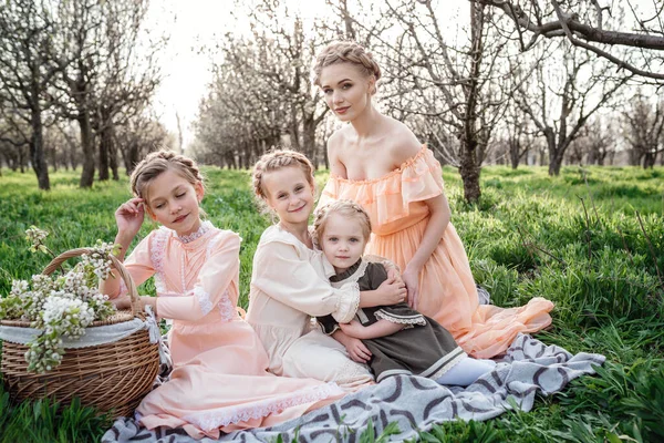 美丽的姑娘和她们的姐姐坐在花园里的花篮上 享受春天的快乐 友好家庭和幸福童年的理念和概念 复古服装 — 图库照片