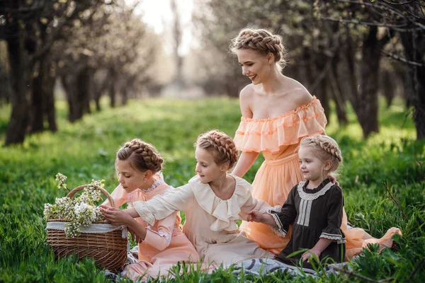 美丽的姑娘和她们的姐姐坐在花园里的花篮上 享受春天的快乐 友好家庭和幸福童年的理念和概念 复古服装 — 图库照片