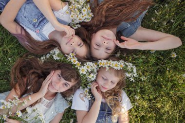 Güneşli bir yaz gününde yeşil çimlerde uzanan ve gülümseyen ya da uyuyan sevimli uzun saçlı genç kızların manzarası. Mutlu bir çocukluk fikri ve konsepti