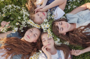 Güneşli bir yaz gününde yeşil çimlerde uzanan ve gülümseyen ya da uyuyan sevimli uzun saçlı genç kızların manzarası. Mutlu bir çocukluk fikri ve konsepti