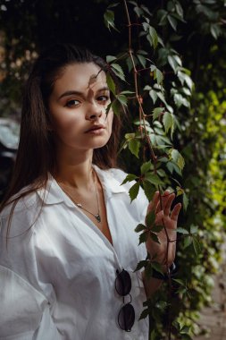 Yeşil yapraklı genç hippi kadının moda portresi. Beyaz gömlekli bir esmerin güzel duygusal portresi.