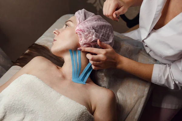 Female Cosmetician Doing Taping Face Patient Lying Desk Home Physiotherapy — Stock Photo, Image