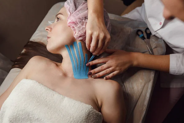 Female Cosmetician Doing Taping Face Patient Lying Desk Home Physiotherapy — Stock Photo, Image