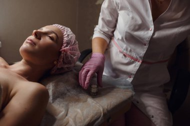 Güzellik tedavisi konsepti. Yüzüne beyaz nemlendirici kumaş maskeli güzel bir kadın. Spa, cilt bakımı, cilt temizleme ve nemlendirici prosedürler. Sağlık ve rahatlama..