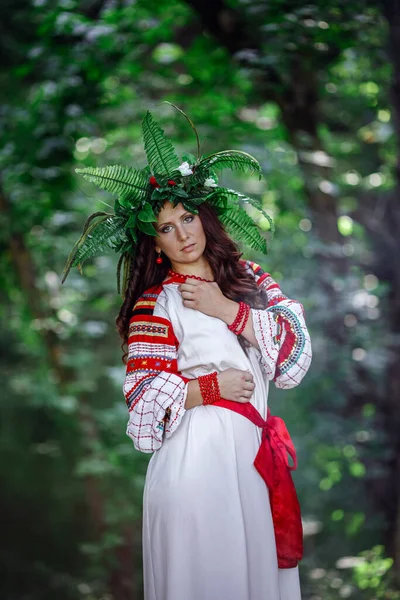 晴れた日に野生の花のリースの美しい女性 赤の民族刺繍が施された白いドレスのパガンスラブの成人女性は真夏に儀式を行います アースデイまたはイヴァナ クパラ — ストック写真