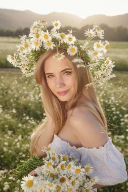 Çayırda güzel sarışın bir kadının portresi kameraya bakıyor ve bahar akşamının tadını çıkarıyor. Beyaz kadın parkta rahatlıyor, papatya dışarıda fotokopi odası var.