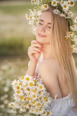 Çayırda güzel sarışın bir kadının portresi kameraya bakıyor ve bahar akşamının tadını çıkarıyor. Beyaz kadın parkta rahatlıyor, papatya dışarıda fotokopi odası var.