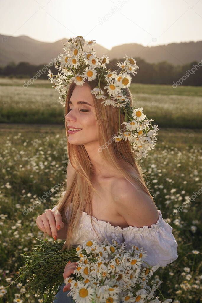 portrait of a beautiful blonde woman on meadow looking to the camera and enjoying nature spring evening outdoors. Caucasian woman relaxation in the park with daisy outside with copy space, cover